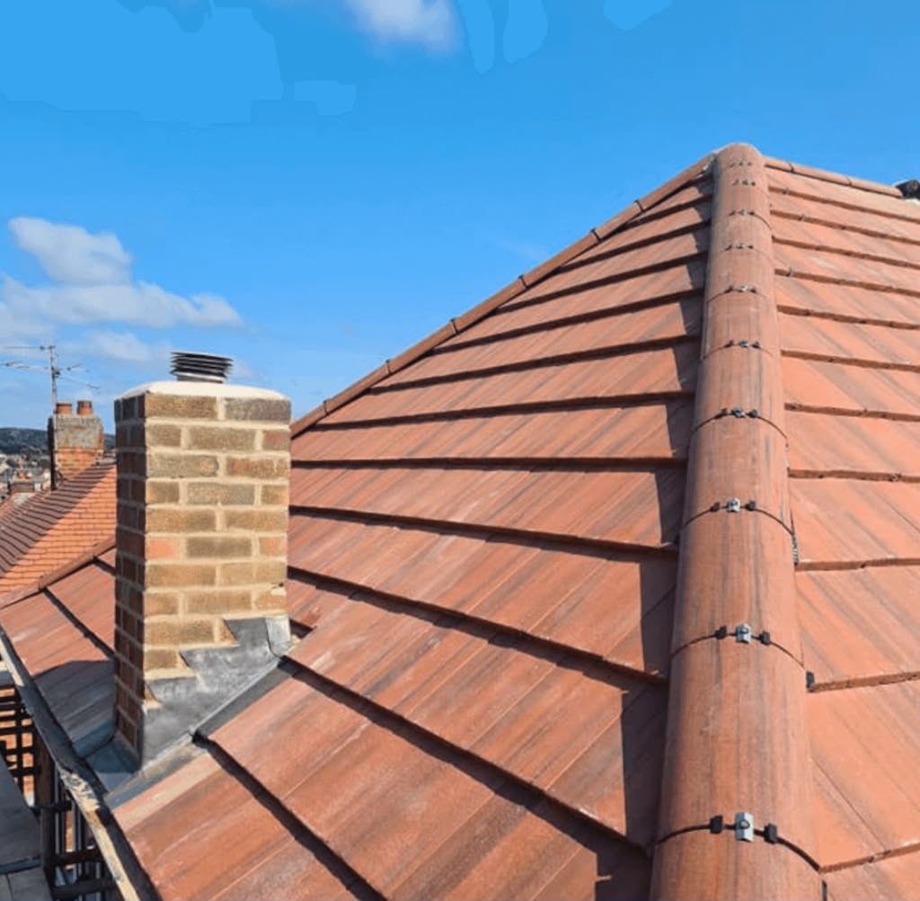Completed terracotta tiled roof with ridge tiles and chimney